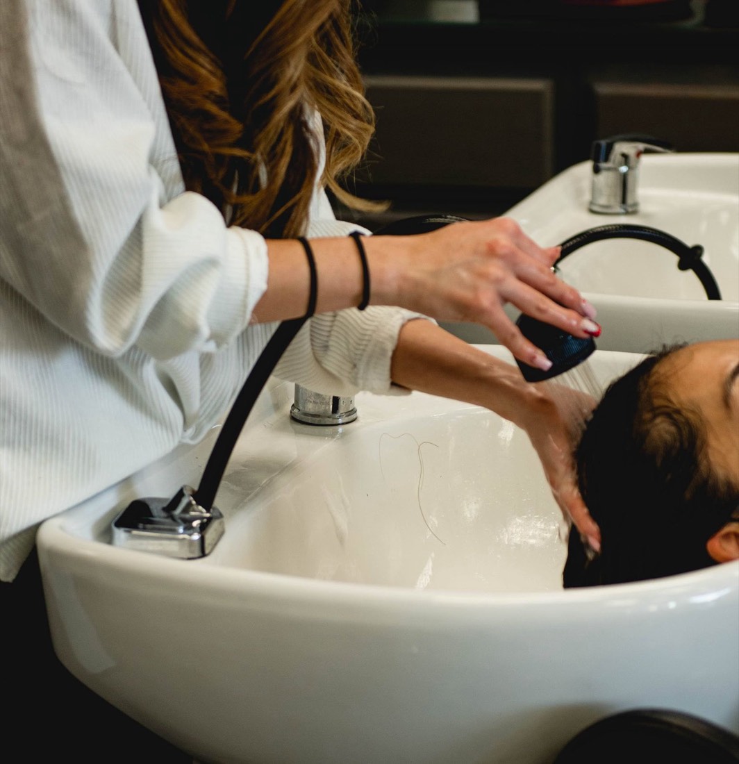 Stylist washing a client’s hair at the salon basin